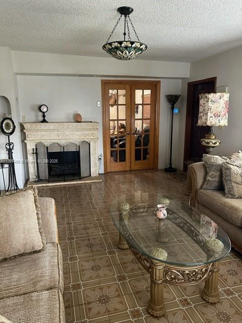 living area with a fireplace with raised hearth, french doors, a textured ceiling, and arched walkways