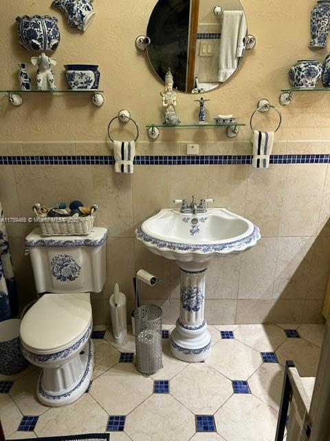 bathroom with toilet, tile walls, and tile patterned floors