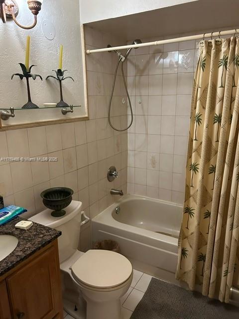 full bath featuring toilet, vanity, tile walls, tile patterned floors, and shower / bathtub combination with curtain