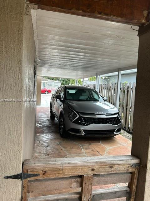 view of parking / parking lot featuring fence and an attached carport