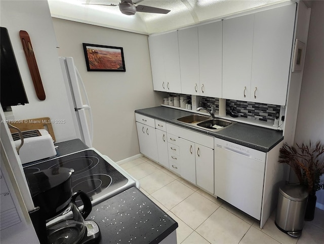 kitchen with white appliances, dark countertops, a sink, backsplash, and light tile patterned flooring