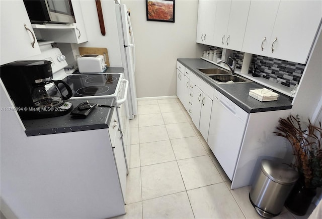 kitchen with dark countertops, white appliances, light tile patterned flooring, and a sink