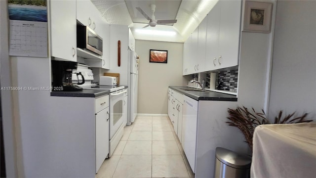 kitchen with light tile patterned floors, tasteful backsplash, dark countertops, a sink, and white appliances