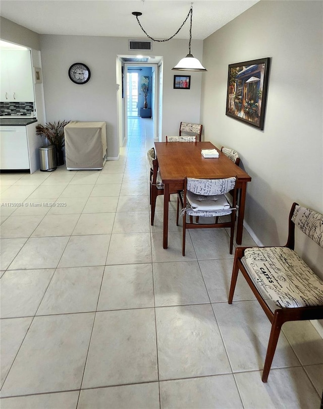 dining room featuring lofted ceiling, light tile patterned floors, baseboards, and visible vents