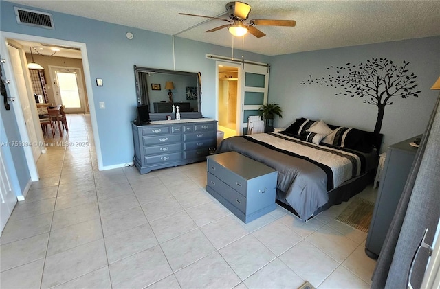 bedroom with light tile patterned floors, a textured ceiling, visible vents, baseboards, and a ceiling fan