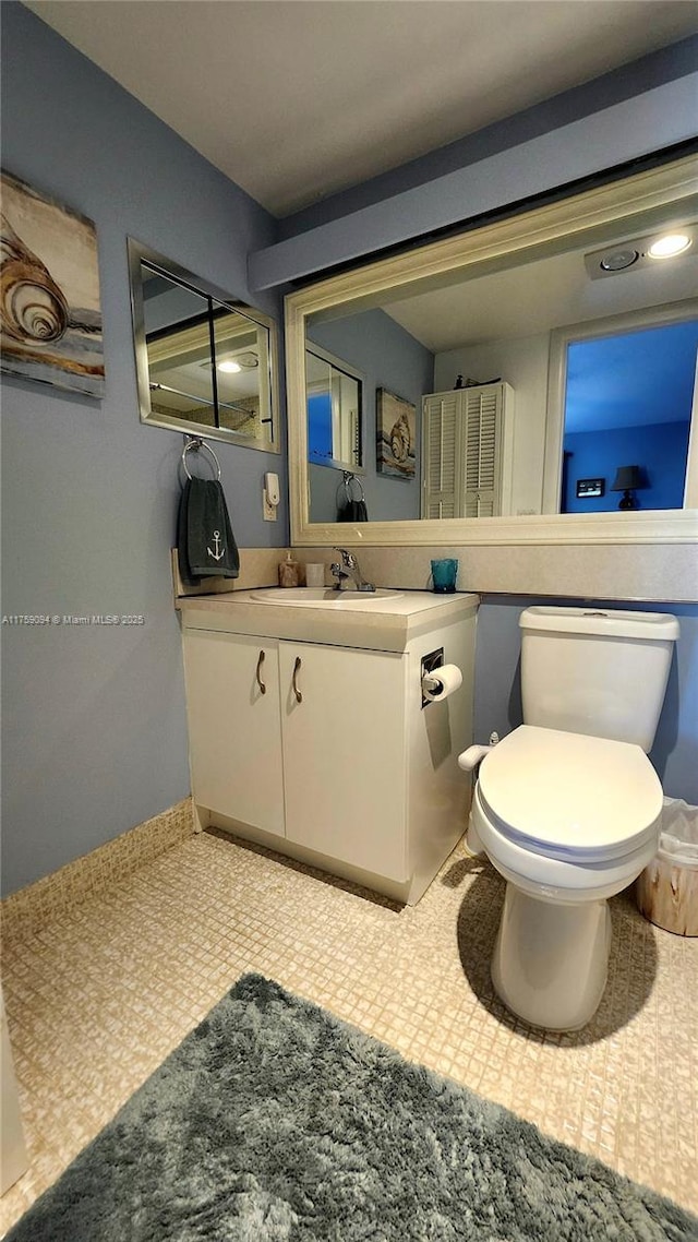 bathroom featuring toilet, baseboards, and vanity