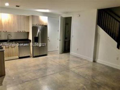 kitchen with stainless steel fridge, concrete floors, baseboards, and modern cabinets