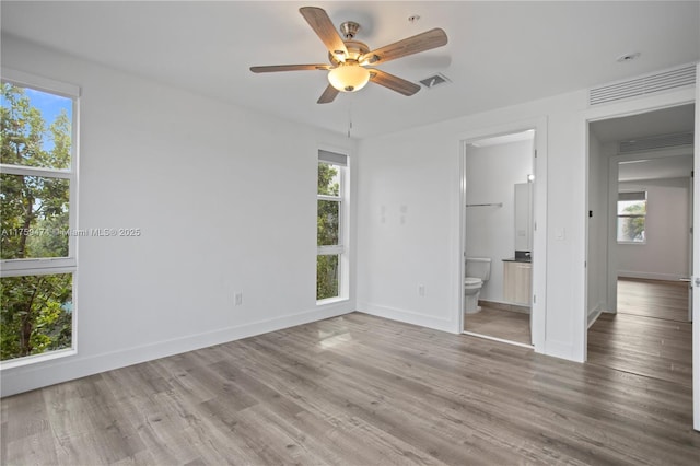 unfurnished bedroom with visible vents, baseboards, wood finished floors, and multiple windows