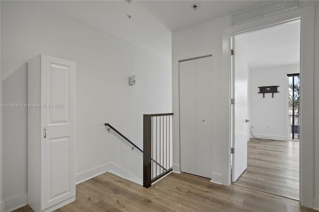 stairway featuring baseboards, wood finished floors, and visible vents