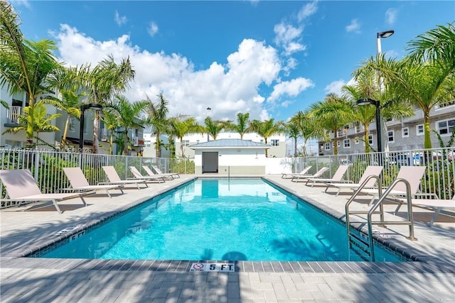 pool with fence, a patio, and a residential view