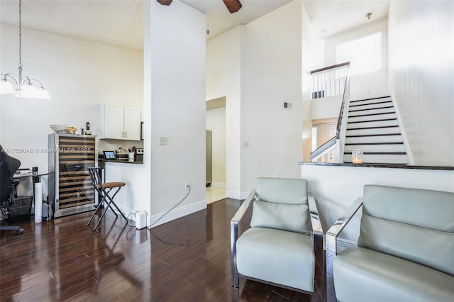 interior space with visible vents, a towering ceiling, wood finished floors, baseboards, and ceiling fan with notable chandelier