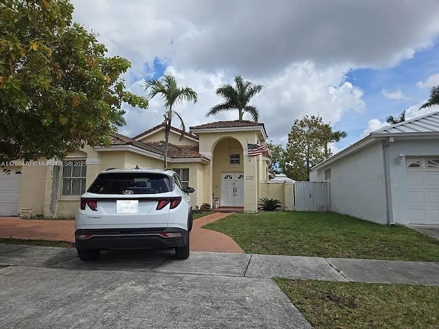 view of front of house featuring stucco siding, a gate, fence, a garage, and a front lawn