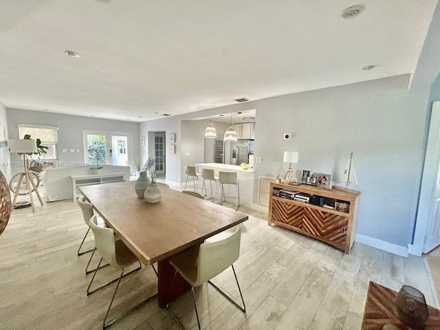 dining space with baseboards, visible vents, and light wood-style floors