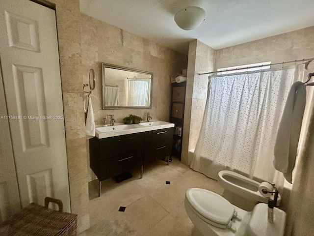 full bath with tile patterned flooring, toilet, a sink, double vanity, and a bidet