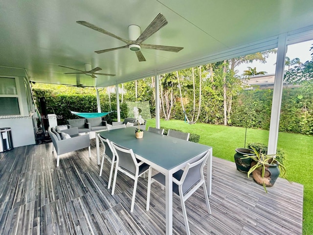 wooden terrace with ceiling fan, outdoor dining area, and a lawn