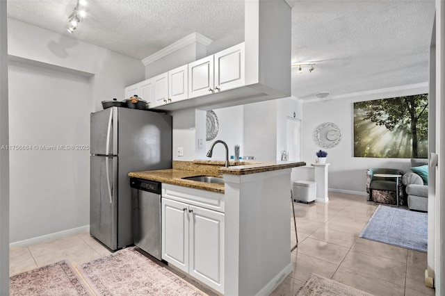 kitchen with light tile patterned floors, appliances with stainless steel finishes, white cabinets, a sink, and a textured ceiling