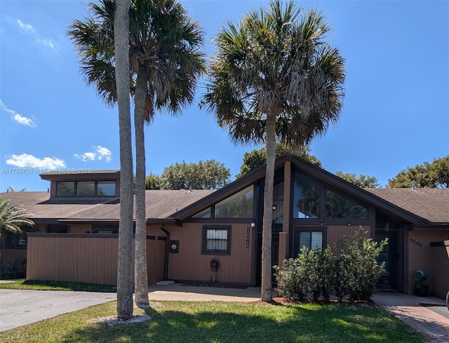 mid-century home with a garage, driveway, a front lawn, and fence