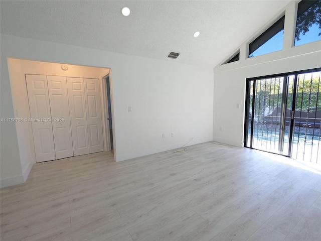 interior space with light wood-type flooring, baseboards, visible vents, and a textured ceiling