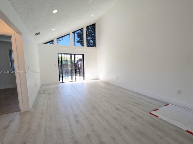 unfurnished room with a textured ceiling, light wood-type flooring, visible vents, and baseboards