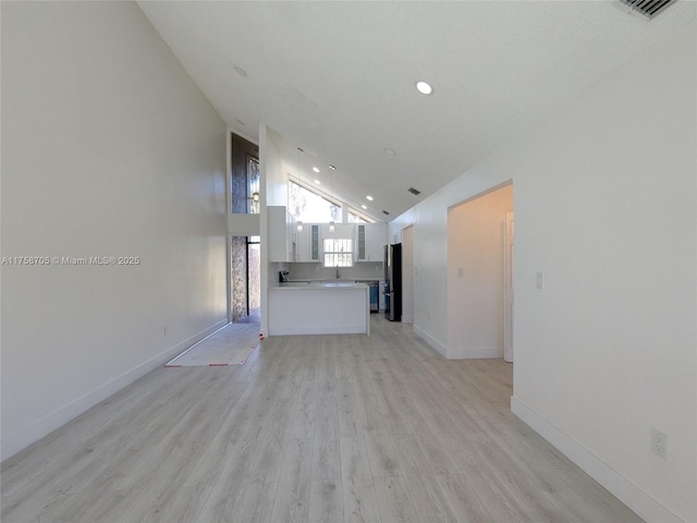 unfurnished living room with light wood finished floors, recessed lighting, visible vents, high vaulted ceiling, and baseboards