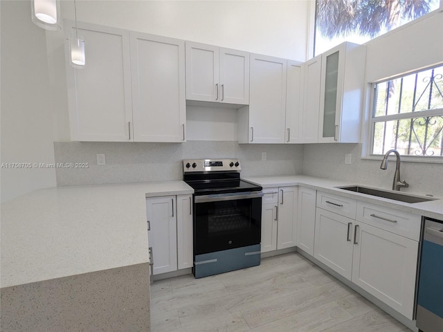 kitchen featuring backsplash, electric range, glass insert cabinets, a sink, and dishwasher