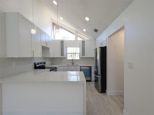 kitchen with stainless steel appliances, light countertops, glass insert cabinets, vaulted ceiling, and a sink