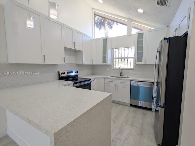 kitchen featuring visible vents, appliances with stainless steel finishes, vaulted ceiling, a sink, and a peninsula