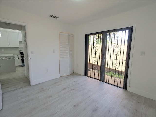 spare room featuring a wealth of natural light, visible vents, light wood-style flooring, and baseboards