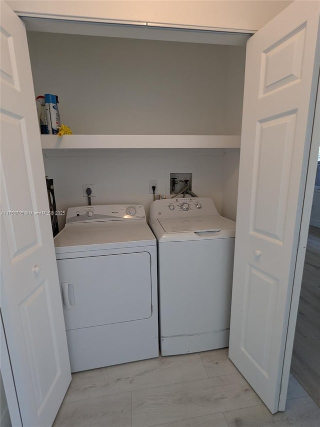 laundry area with laundry area, washing machine and clothes dryer, and light wood-style floors