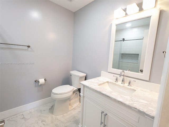 bathroom featuring marble finish floor, toilet, vanity, tiled shower, and baseboards