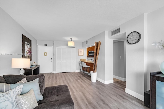 living room featuring wood finished floors, visible vents, and baseboards