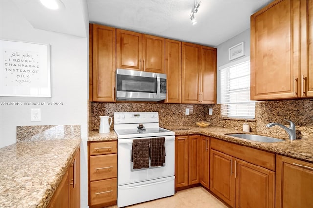 kitchen featuring tasteful backsplash, white range with electric stovetop, brown cabinetry, stainless steel microwave, and a sink