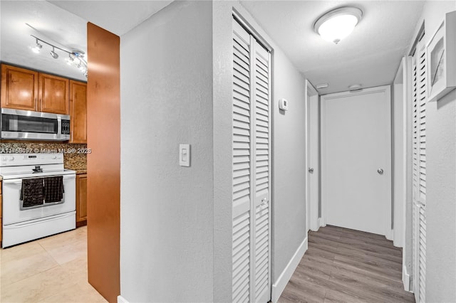 hall featuring light wood-style flooring and baseboards