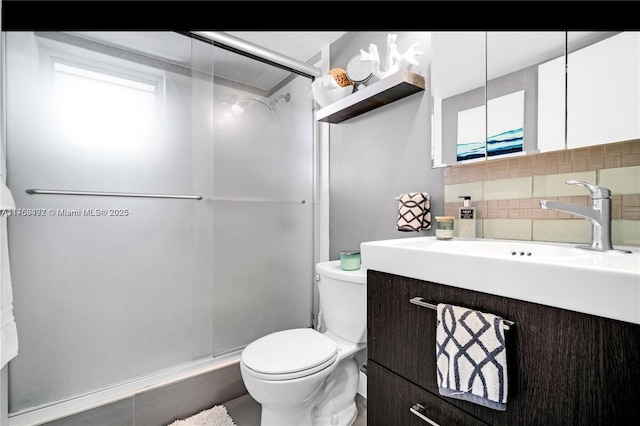 bathroom with a stall shower, toilet, vanity, and decorative backsplash