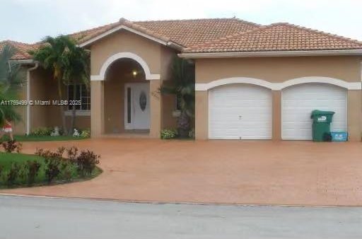 view of front facade featuring stucco siding, concrete driveway, an attached garage, and a tiled roof