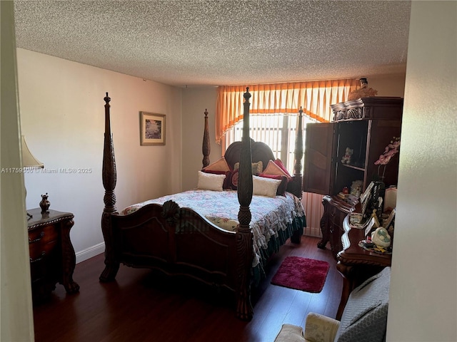 bedroom featuring a textured ceiling, wood finished floors, and baseboards