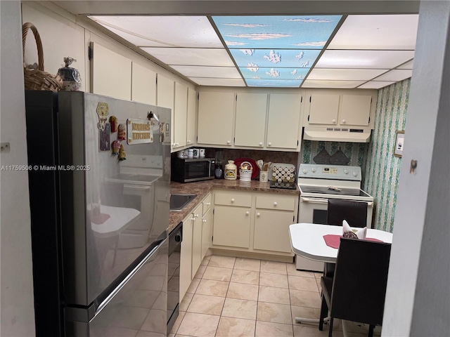 kitchen featuring black dishwasher, white range with electric stovetop, stainless steel microwave, freestanding refrigerator, and under cabinet range hood