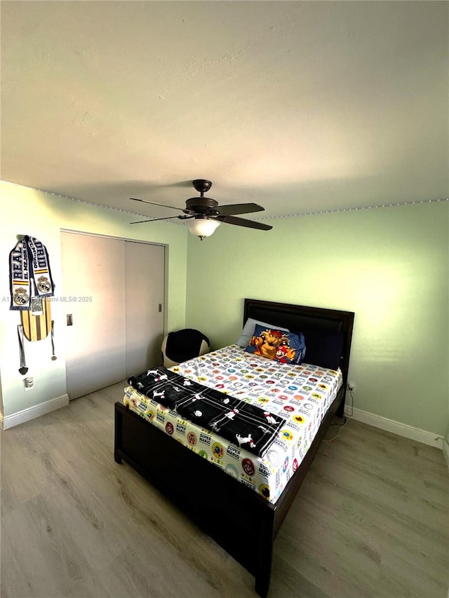 bedroom with light wood-type flooring, baseboards, a closet, and a ceiling fan