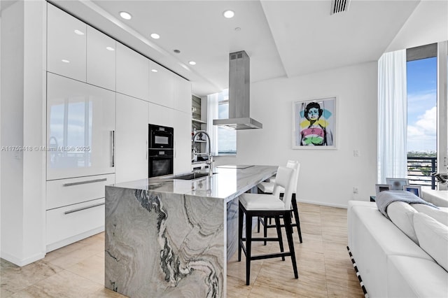 kitchen featuring light stone counters, modern cabinets, island exhaust hood, and visible vents