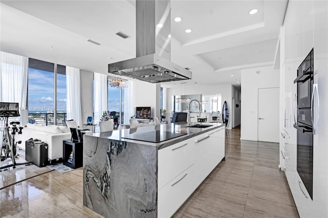 kitchen with island range hood, white cabinets, a large island, modern cabinets, and a sink