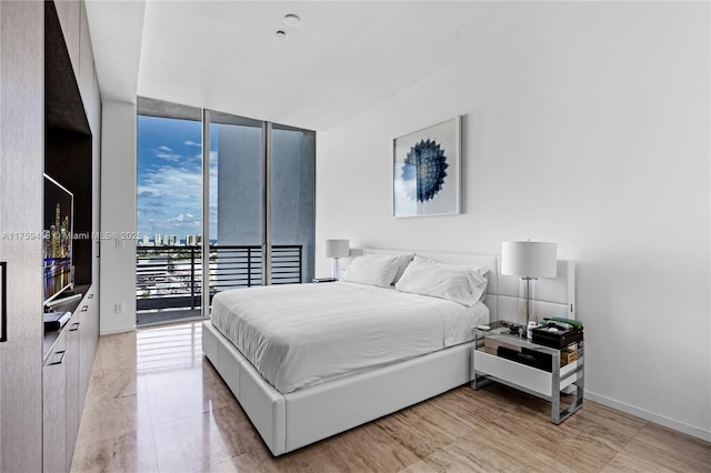 bedroom featuring access to outside, expansive windows, and baseboards