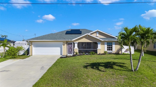 ranch-style home featuring a garage, driveway, a front yard, roof mounted solar panels, and stucco siding