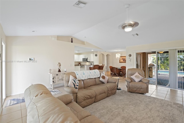 living room featuring lofted ceiling, visible vents, arched walkways, and light tile patterned floors