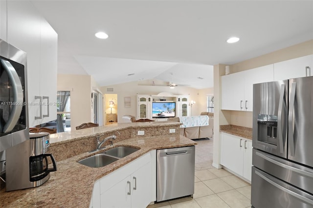 kitchen with lofted ceiling, light stone counters, light tile patterned flooring, a sink, and appliances with stainless steel finishes