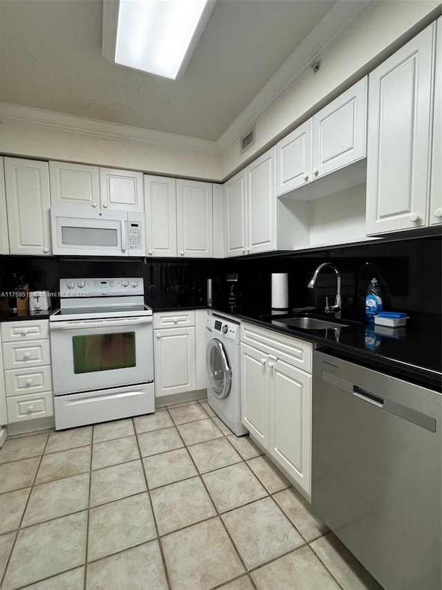 kitchen with white appliances, a sink, white cabinets, washer / dryer, and crown molding