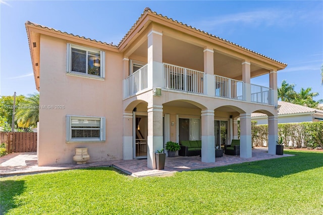 rear view of house featuring a patio area, a yard, a balcony, and stucco siding