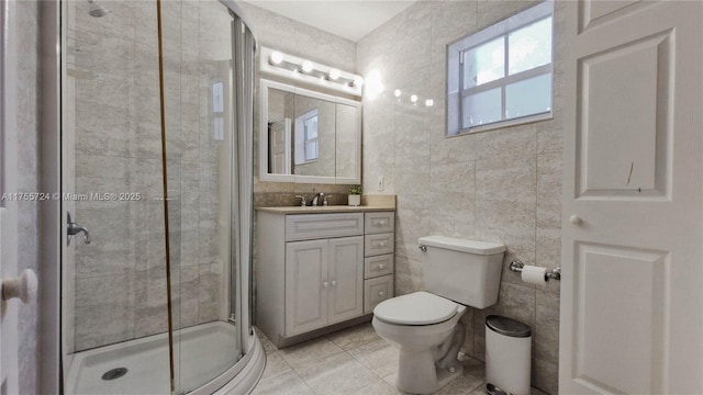 full bathroom featuring tile walls, toilet, a stall shower, vanity, and tile patterned flooring