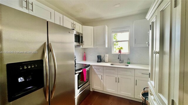 kitchen with white cabinets, decorative backsplash, appliances with stainless steel finishes, light countertops, and a sink