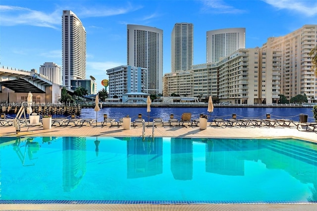 pool featuring a water view, a patio area, and a city view