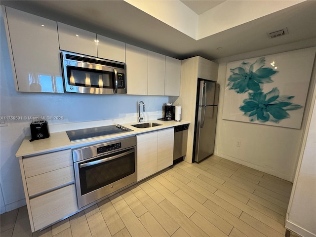 kitchen with stainless steel appliances, a sink, light countertops, and white cabinetry